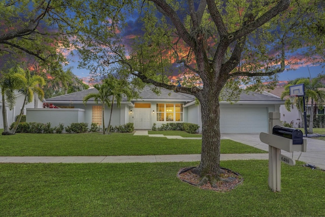 view of front of property featuring a garage, stucco siding, a lawn, and concrete driveway