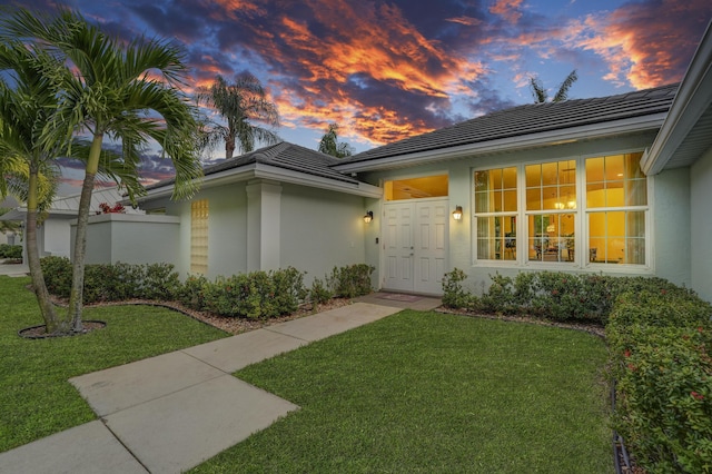 view of front of property with a front yard, a tiled roof, and stucco siding