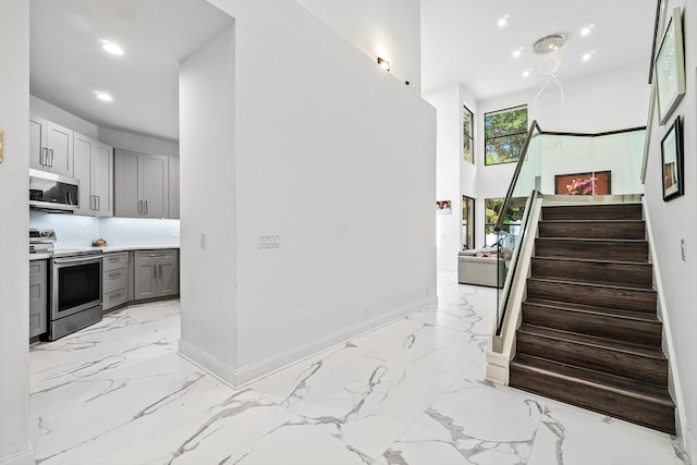 interior space with marble finish floor, recessed lighting, a towering ceiling, and baseboards