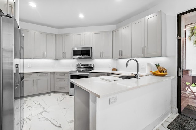 kitchen with appliances with stainless steel finishes, gray cabinets, and a sink