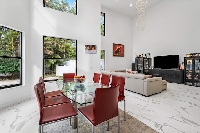 dining area featuring a towering ceiling, marble finish floor, and recessed lighting