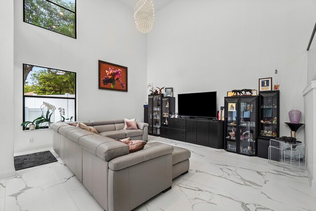 living room featuring a towering ceiling, marble finish floor, and baseboards