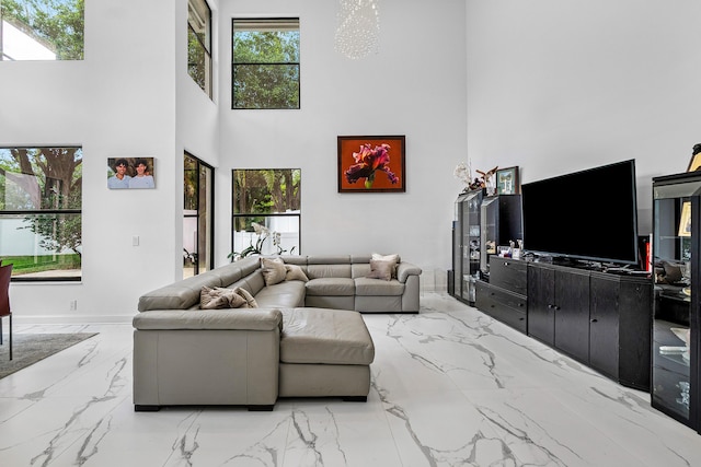 living room featuring a towering ceiling, marble finish floor, and a wealth of natural light