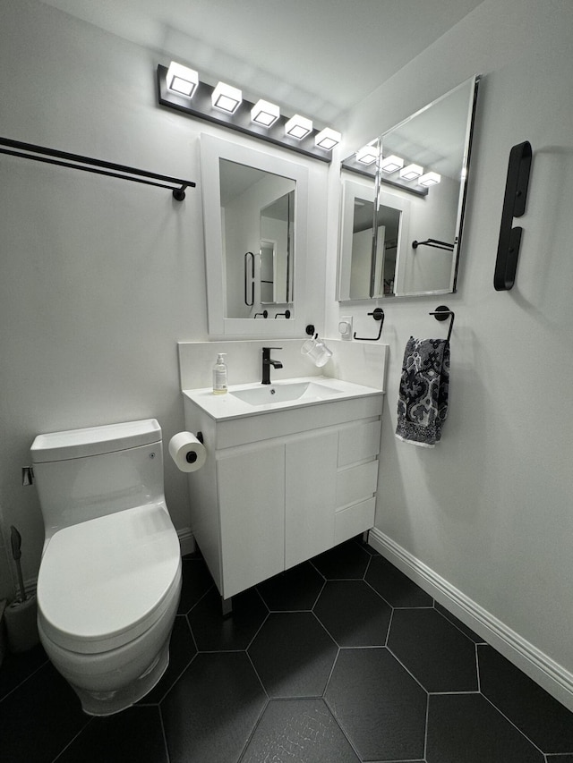 bathroom featuring baseboards, vanity, toilet, and tile patterned floors