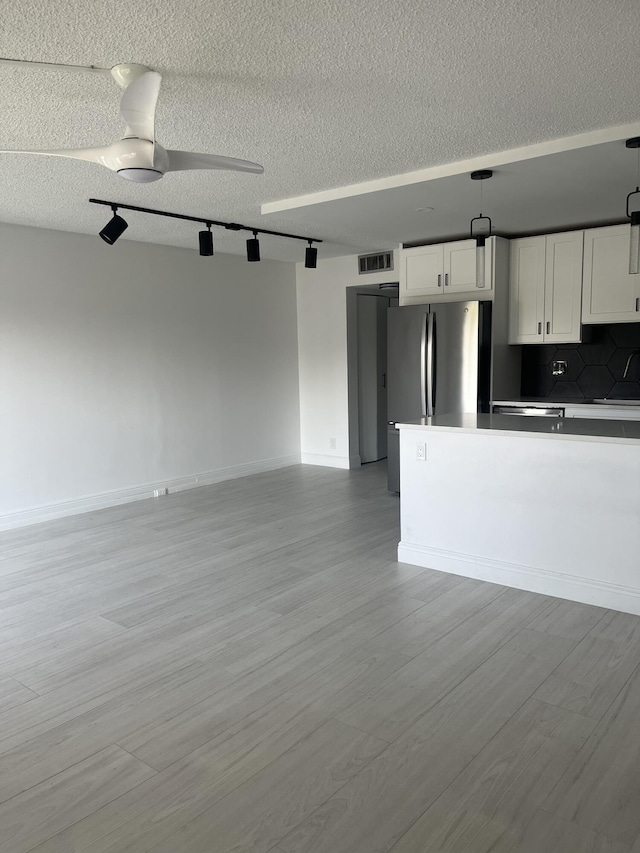 kitchen with ceiling fan, visible vents, white cabinets, open floor plan, and freestanding refrigerator