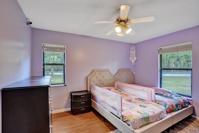 bedroom featuring baseboards, multiple windows, ceiling fan, and light wood finished floors