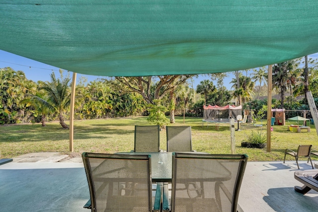 view of patio featuring a trampoline, outdoor dining area, and playground community