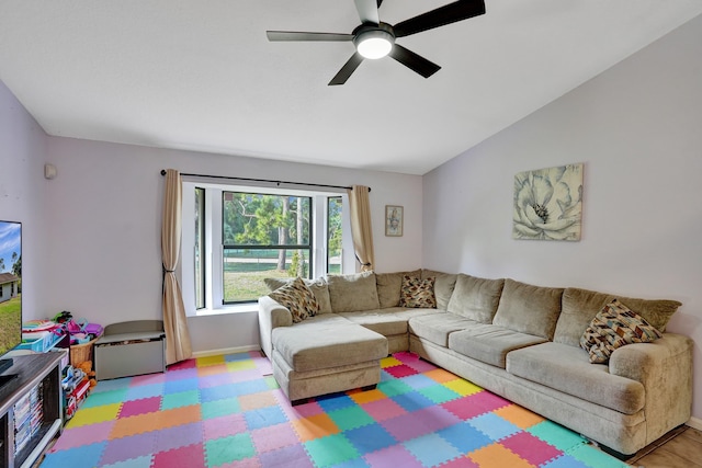 living room featuring lofted ceiling, ceiling fan, and baseboards