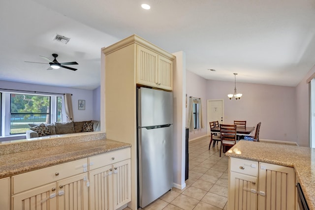 kitchen featuring freestanding refrigerator, cream cabinets, vaulted ceiling, pendant lighting, and light tile patterned flooring