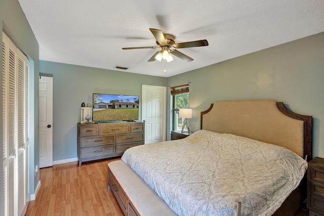 bedroom featuring a closet, visible vents, light wood-style flooring, ceiling fan, and baseboards