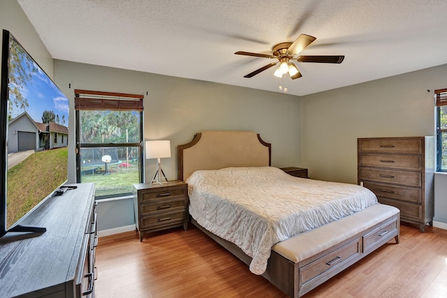 bedroom featuring light wood-style flooring, baseboards, and a textured ceiling