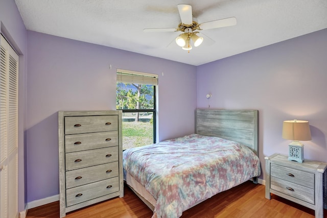 bedroom featuring a ceiling fan, a closet, baseboards, and wood finished floors