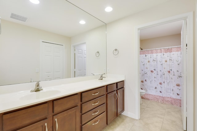 bathroom featuring toilet, double vanity, visible vents, and a sink