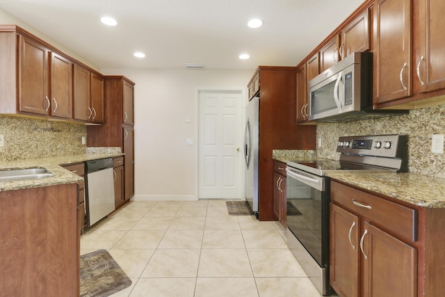 kitchen with light tile patterned floors, light stone counters, stainless steel appliances, a sink, and visible vents