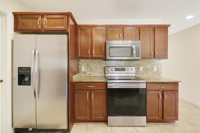 kitchen featuring light stone counters, brown cabinets, light tile patterned floors, stainless steel appliances, and backsplash