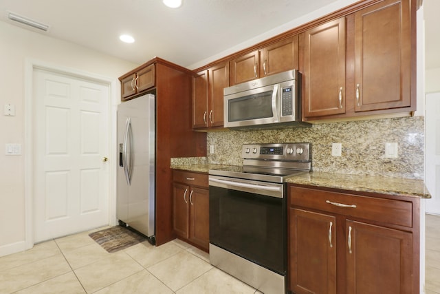 kitchen featuring light tile patterned floors, light stone counters, stainless steel appliances, visible vents, and tasteful backsplash