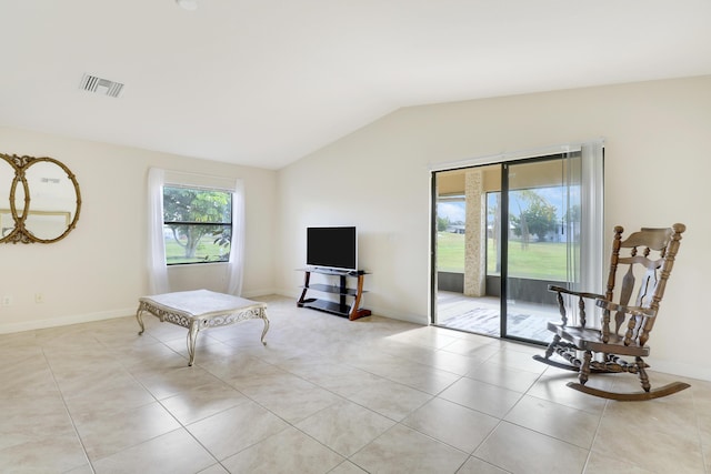 living area with vaulted ceiling, light tile patterned floors, visible vents, and baseboards