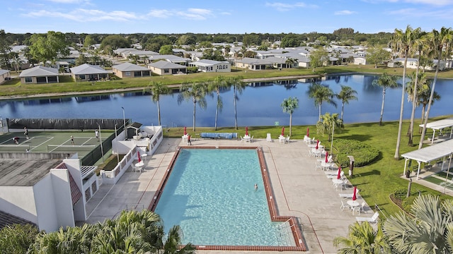 view of swimming pool featuring a water view, a residential view, and fence