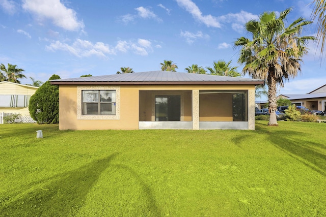 back of property featuring a sunroom, a yard, and stucco siding