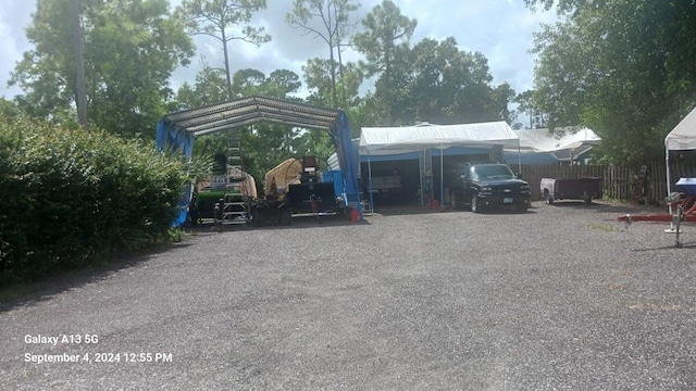 view of parking / parking lot with a carport and fence