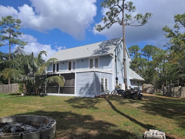 back of house with a fire pit, french doors, a sunroom, fence, and a yard