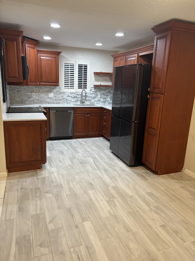 kitchen with dishwasher, light countertops, freestanding refrigerator, and a sink