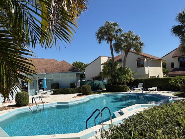 community pool with a patio area and fence