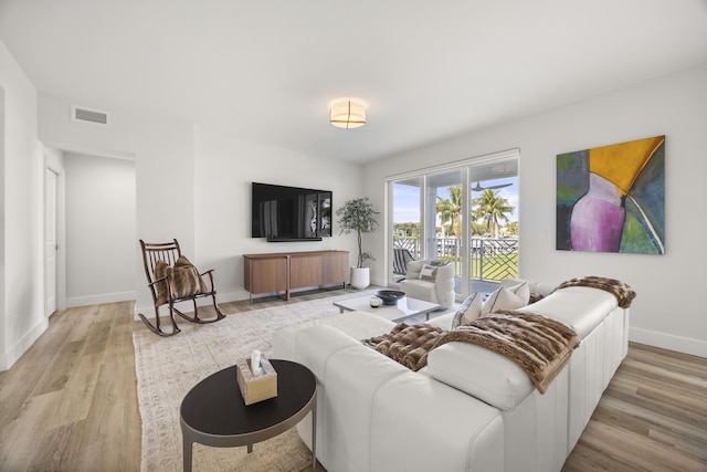 living area featuring light wood-style floors, baseboards, and visible vents