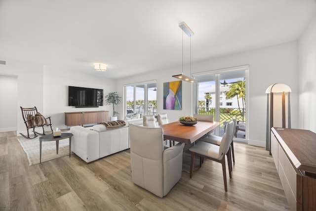 dining room with light wood finished floors, visible vents, and baseboards