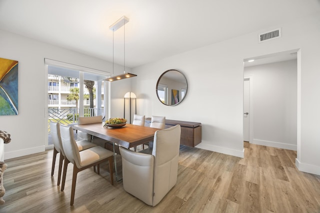 dining area featuring light wood-type flooring, visible vents, and baseboards