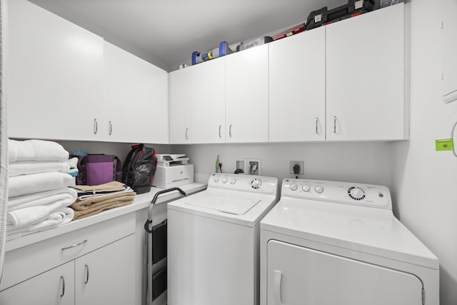 clothes washing area with washer and clothes dryer and cabinet space