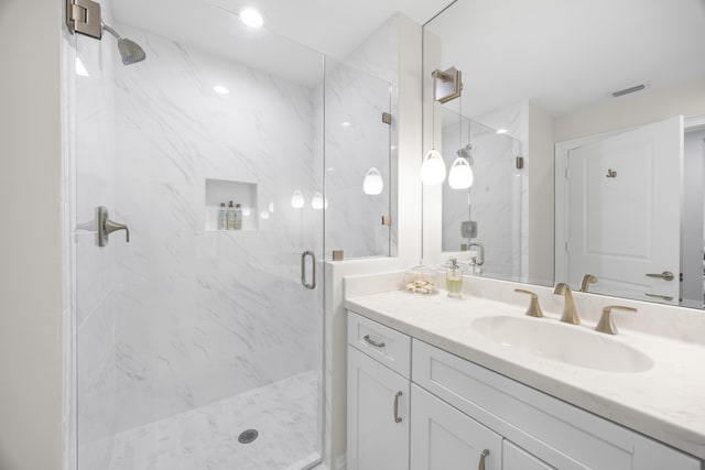 bathroom with visible vents, a marble finish shower, and vanity