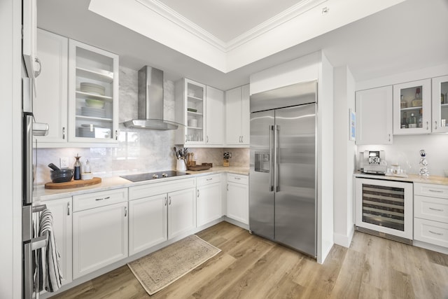 kitchen featuring white cabinets, wall chimney exhaust hood, wine cooler, built in refrigerator, and black electric cooktop