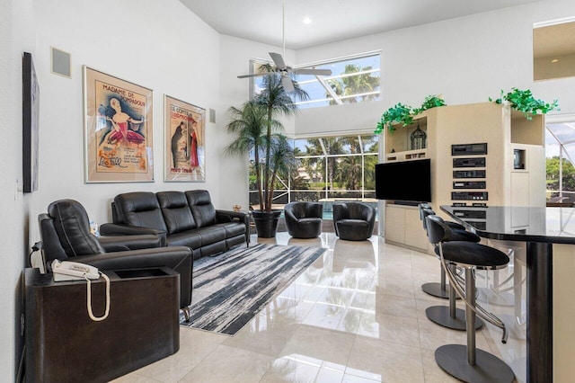 living room featuring a ceiling fan, visible vents, a high ceiling, and light tile patterned floors