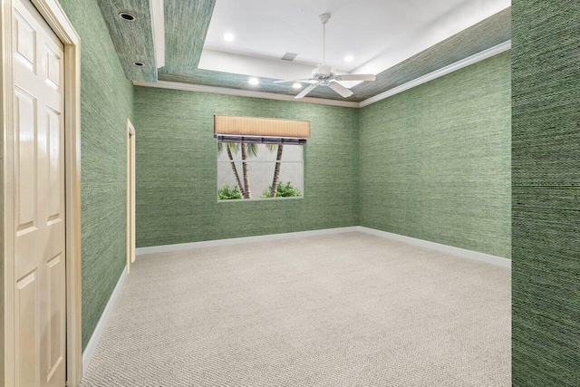 carpeted empty room with wallpapered walls, baseboards, a tray ceiling, and a ceiling fan