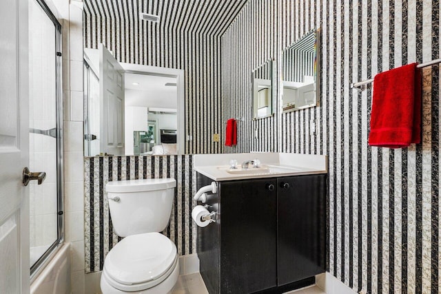 full bath featuring shower / bath combination with glass door, vanity, toilet, and wallpapered walls