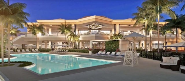 pool at twilight featuring a patio area, a community pool, and fence