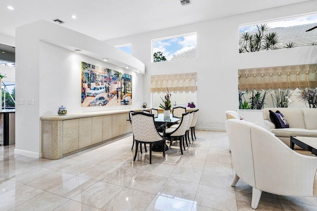 dining space featuring a high ceiling, plenty of natural light, and baseboards