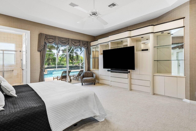 carpeted bedroom with ceiling fan, access to outside, a tray ceiling, and visible vents