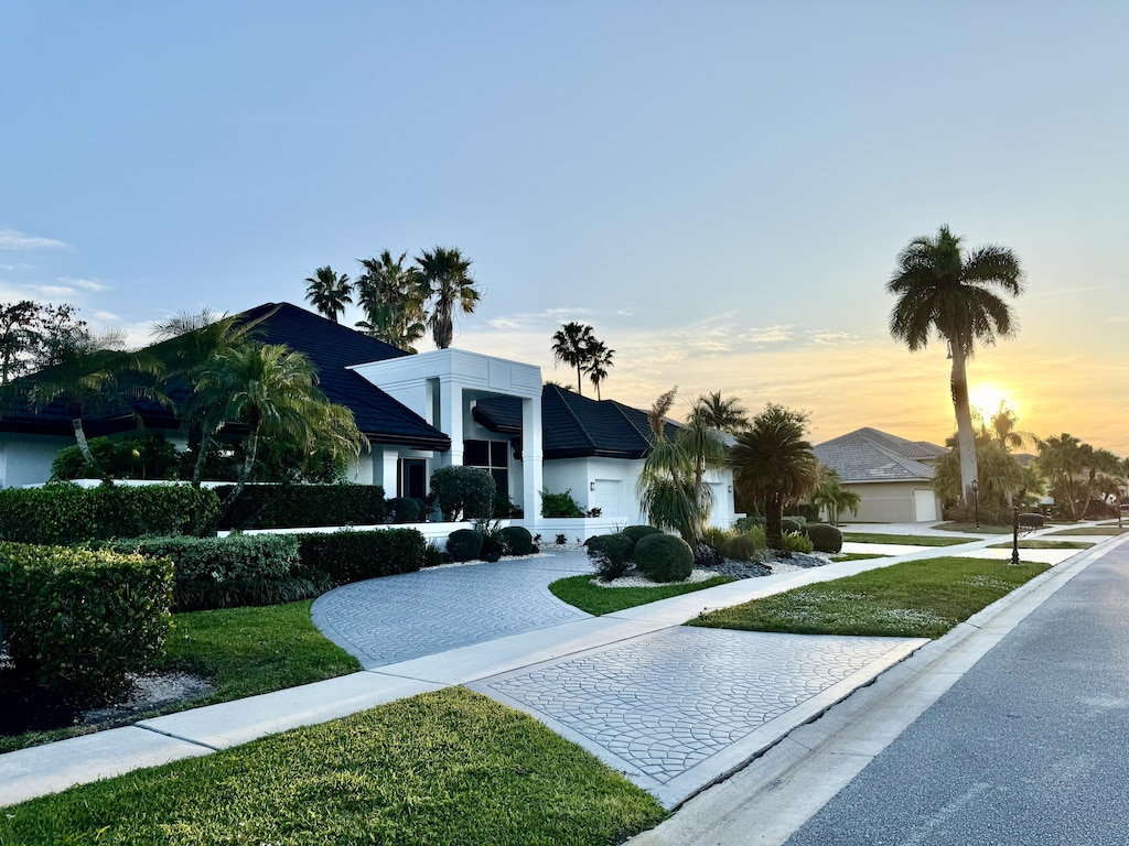 view of front facade with a front lawn, decorative driveway, and stucco siding