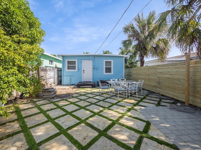 rear view of property with a patio area, a fenced backyard, outdoor dining space, and an outbuilding