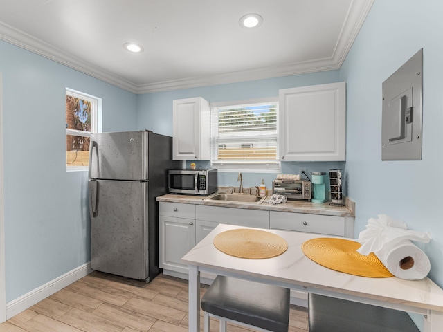 kitchen with crown molding, appliances with stainless steel finishes, white cabinets, a sink, and electric panel