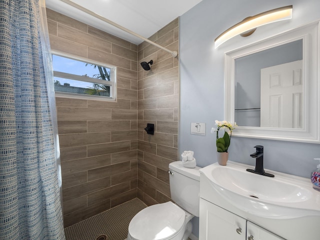 bathroom featuring tiled shower, vanity, and toilet