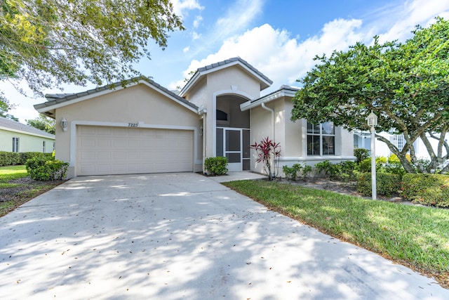 ranch-style home featuring driveway, an attached garage, and stucco siding