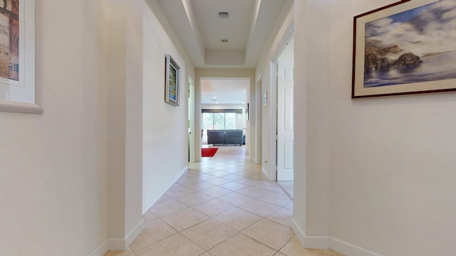 hallway with light tile patterned floors, visible vents, and baseboards