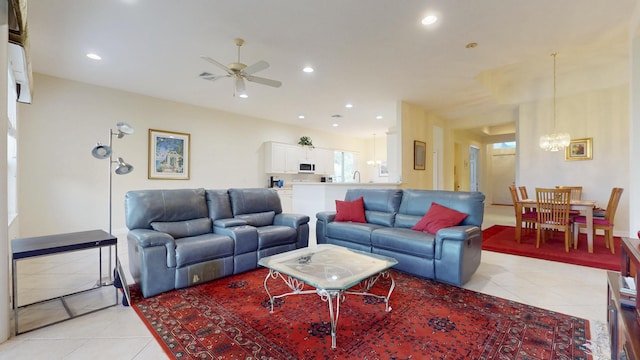 living area with light tile patterned floors, ceiling fan with notable chandelier, and recessed lighting