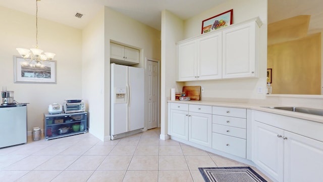 kitchen featuring light tile patterned floors, white refrigerator with ice dispenser, visible vents, light countertops, and fridge