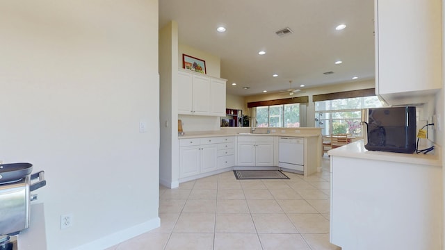 kitchen with light tile patterned floors, visible vents, a sink, dishwasher, and a peninsula