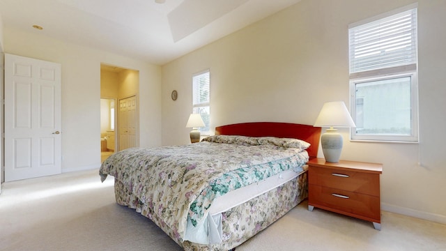 bedroom with light carpet, baseboards, and ensuite bathroom