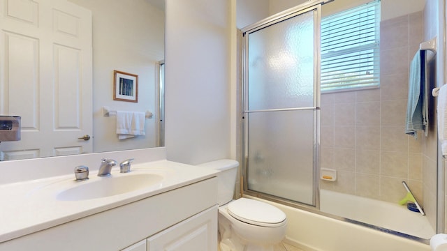 bathroom featuring combined bath / shower with glass door, vanity, and toilet